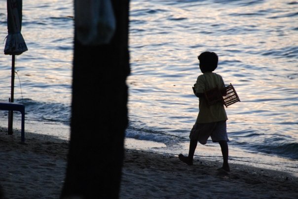 A young street vendor walking down Pattaya Beach
